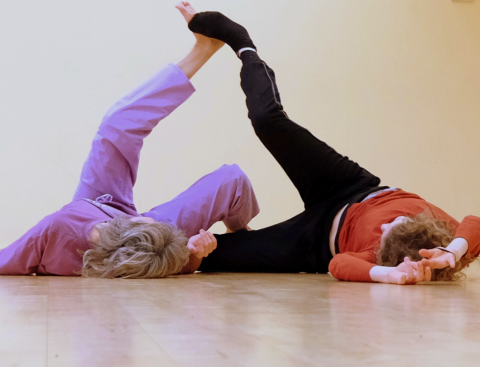 Two dancers, their feet in the air and making contact with each other