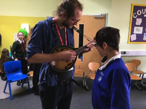 A musician plays a mandolin, a child is watching closely