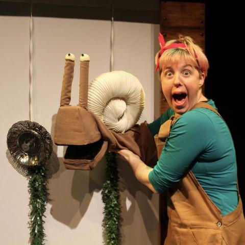 Emma Boor holds snail puppet and looks comically into the camera