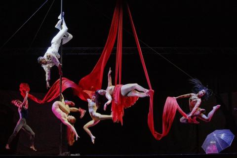 Cabaret performers hang from red silks in various dance positions