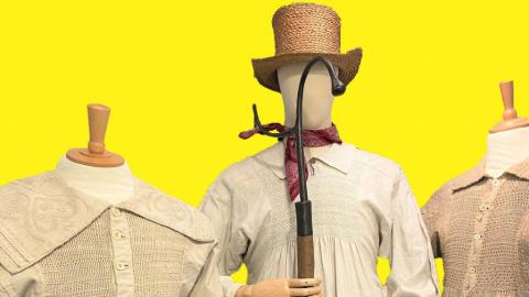 Yellow background. Three mannequins, each wearing a smock. The central one wears a tall straw hat, a shepherd's crook and red neckerchief.