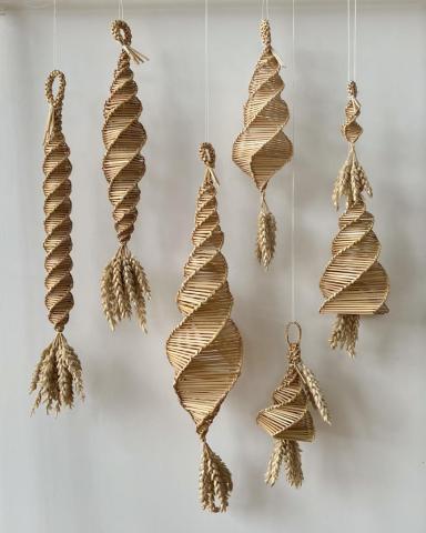 Corn dollies of different sizes and designs suspended in a row.